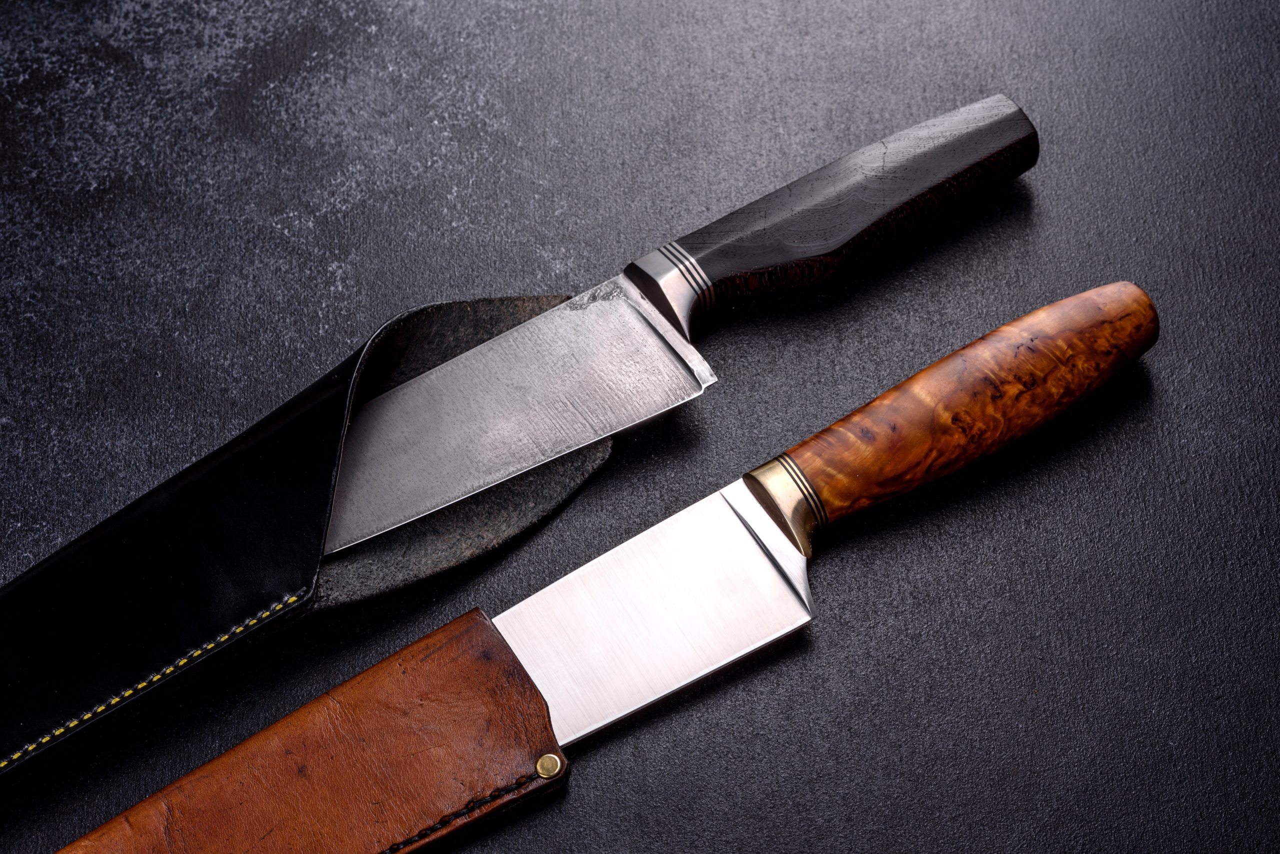 A large handmade hunting knife lying on a dark monotone background